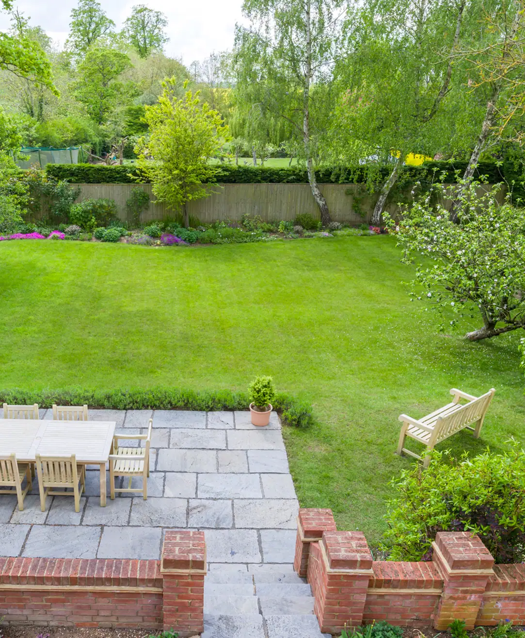 Family garden with lawn and stone terrace for outdoor dining.