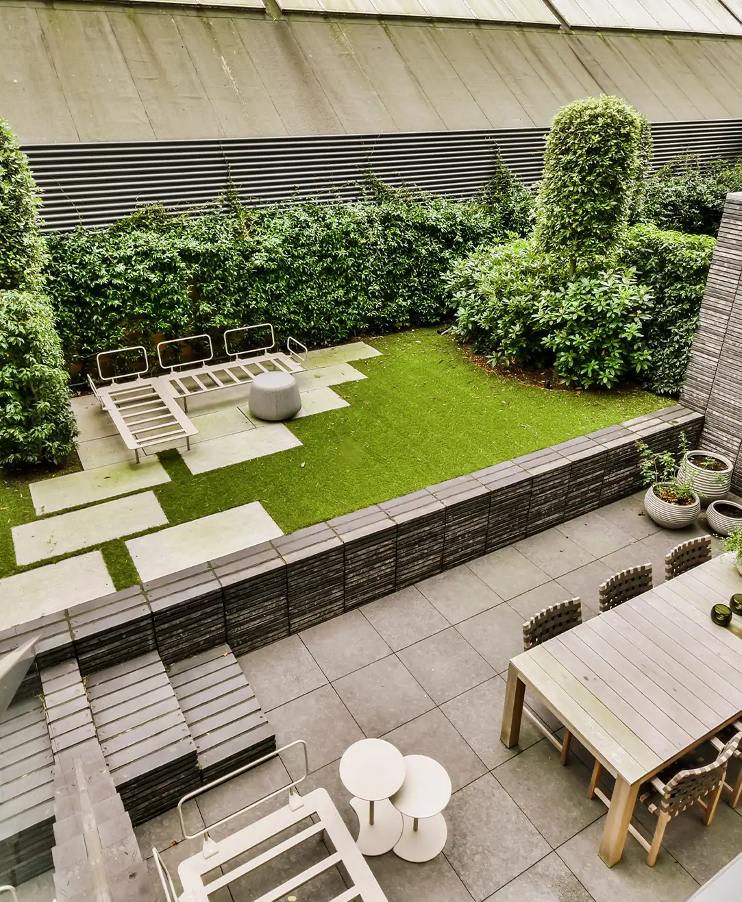 Contemporary residential garden with stepped lawn, paving and seating.