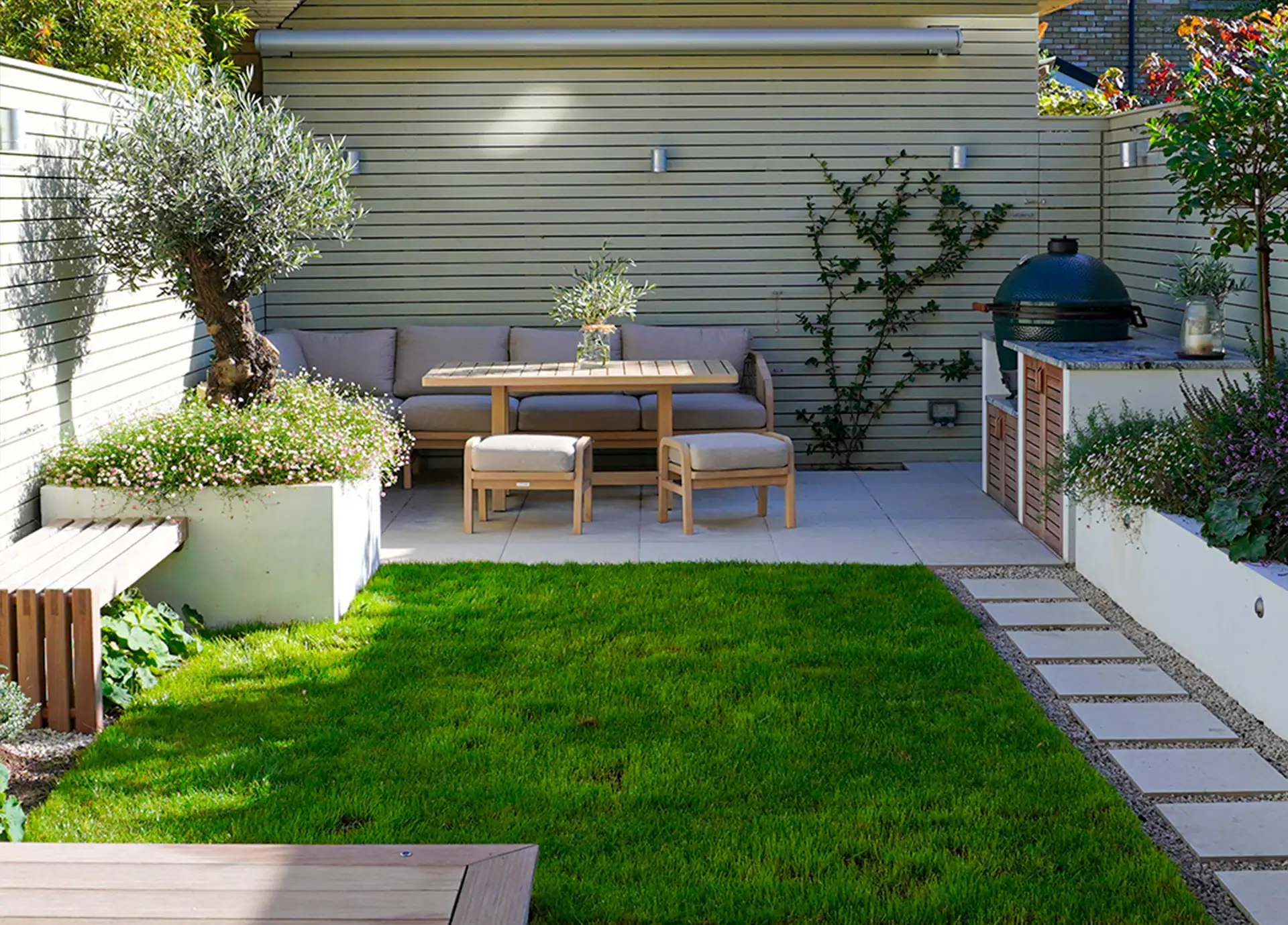 Small Mediterranean-style garden design in Surbiton featuring built-in seating, outdoor kitchen and lawn