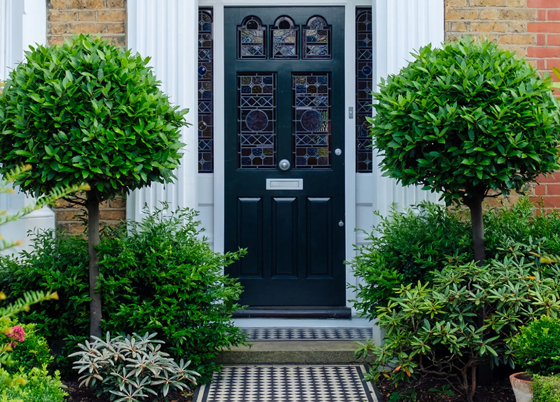 Front garden planting framing a residential entrance with clipped shrubs.