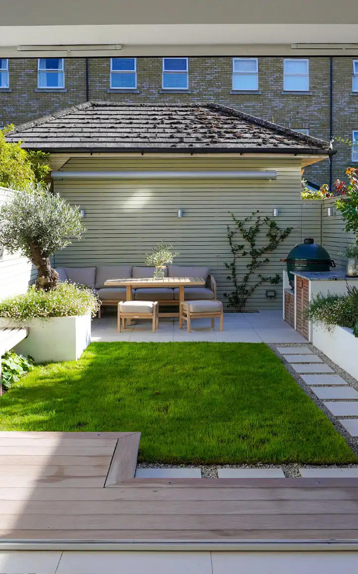 Compact Mediterranean garden layout in Surbiton with lawn, seating area and olive tree planter